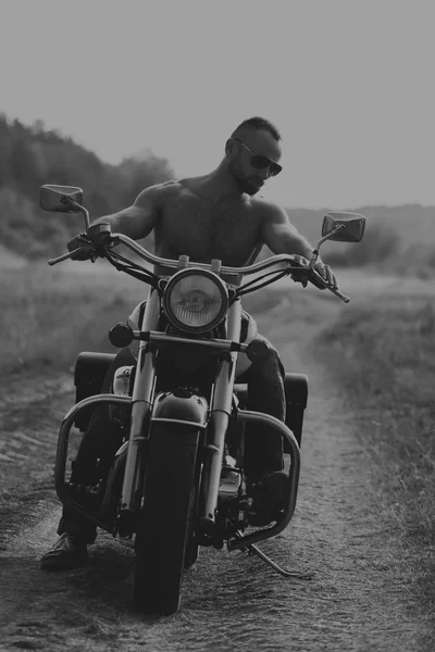 Cool muscular guy on a motorcycle — Stock Photo, Image