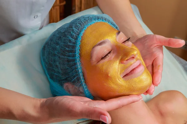 Applicazione di maschere dorate sul volto del modello. Procedure cosmetiche — Foto Stock