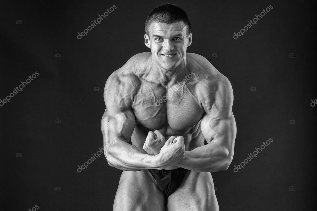 ボディービルダーの筋肉を示すさまざまなポーズでポーズをとるします 暗い背景上に失敗しました 男性を示す筋肉に負担をかけます 美しい筋肉体アスリート ストック写真 C llm