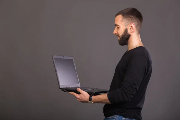 Der Typ mit dem Laptop auf grauem Hintergrund — Stockfoto