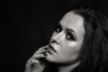 Karanlık bir arka plan üzerinde güzel, gizemli, şirin esmer. Siyah ve beyaz fotoğraf güzel gizemli esmer.