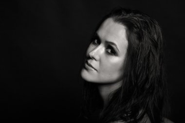 Karanlık bir arka plan üzerinde güzel, gizemli, şirin esmer. Siyah ve beyaz fotoğraf güzel gizemli esmer.