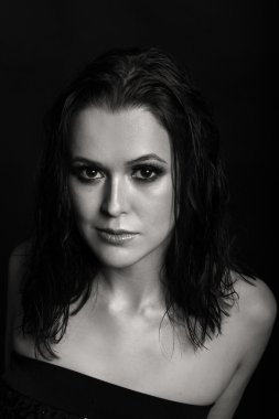 Karanlık bir arka plan üzerinde güzel, gizemli, şirin esmer. Siyah ve beyaz fotoğraf güzel gizemli esmer.