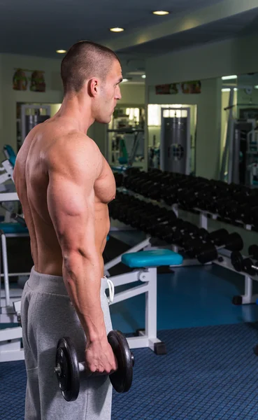 Culturista en el gimnasio. Fuerte realiza ejercicios para bíceps — Foto de Stock