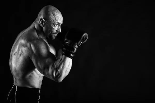 Bodybuilder avec gants de boxe sur fond noir — Photo