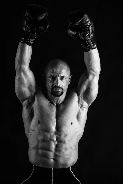 Bodybuilder avec gants de boxe sur fond noir — Photo