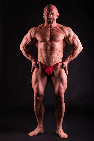 Bodybuilder in demonstrativer Pose auf Schwarz — Stockfoto