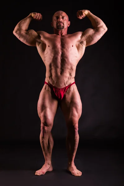 Bodybuilder i demonstrativa poser på svart — Stockfoto