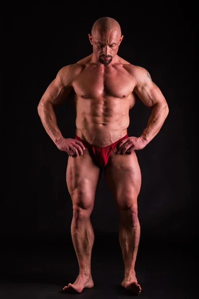 Bodybuilder in demonstrative poses on black — Stock Photo, Image