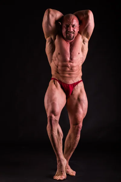 Bodybuilder in demonstrativer Pose auf Schwarz — Stockfoto