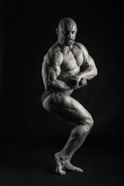 Bir adam siyah bir zemin üzerine muhteşem bir kas vücut ile