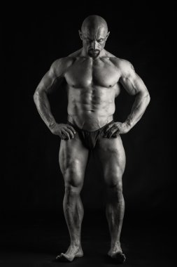 Bir adam siyah bir zemin üzerine muhteşem bir kas vücut ile