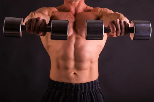 Uomo muscoloso con manubri su nero — Foto Stock