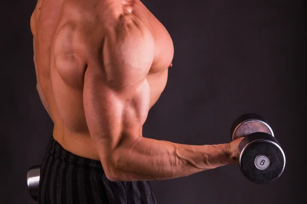 Muscular man with dumbbells on black — Stock Photo, Image