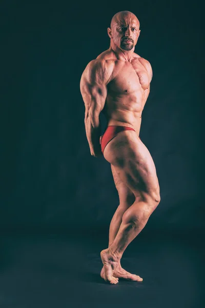 Musculación, hombre fuerte en negro — Foto de Stock