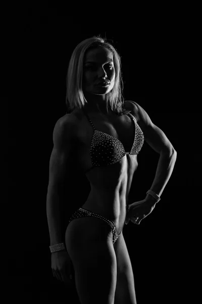 Entrenamiento elegante, mujer musculosa sobre un fondo negro — Foto de Stock