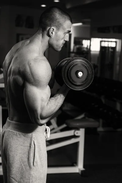 Un uomo si allena in palestra con i manubri. Uno stile di vita sano e — Foto Stock