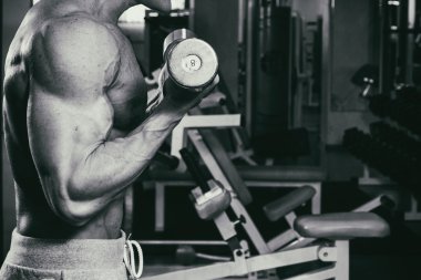 Spor salonunda dumbbells ile bir meslek. Güçlü adam dumbbells ile