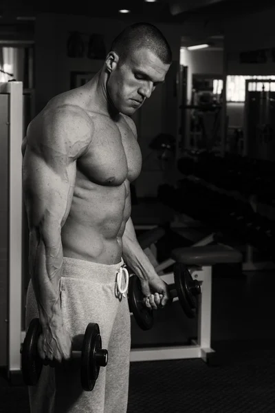 Un uomo si allena in palestra con i manubri. Uno stile di vita sano e — Foto Stock