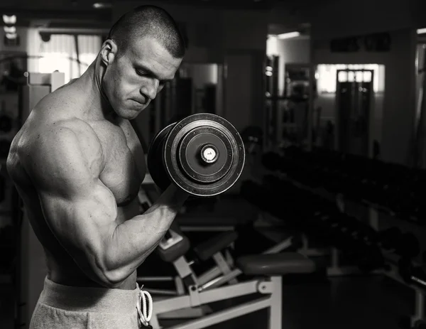 Un uomo si allena in palestra con i manubri. Uno stile di vita sano e — Foto Stock