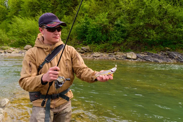 Un pescatore catturato trota sul fiume di montagna — Foto Stock