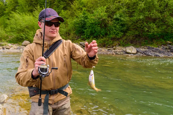 En fiskare fångade öring på floden berg — Stockfoto