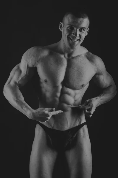 Muscular, relief body bodybuilder on a black background. Black a — Stock Photo, Image