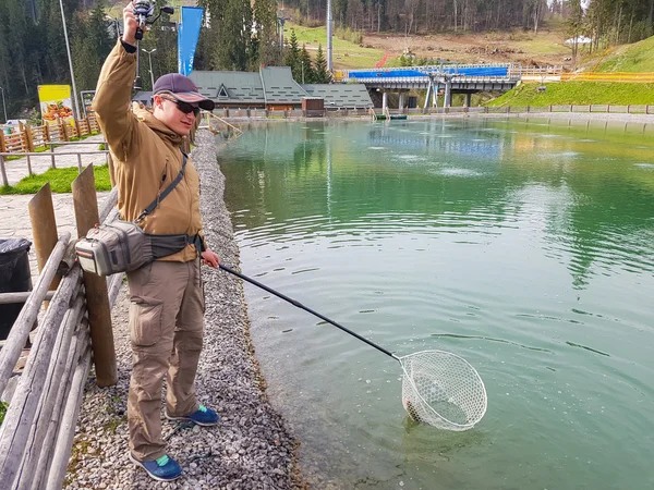 Pesca alla trota nello stagno. Zona di pesca. Pescatore cattura un tro — Foto Stock