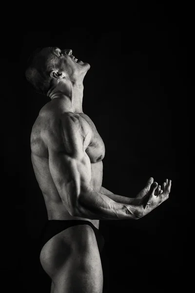М'язистий, рельєфний культурист на чорному тлі — стокове фото
