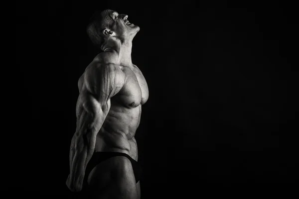 Gespierd, opluchting bodybuilder op een zwarte achtergrond — Stockfoto