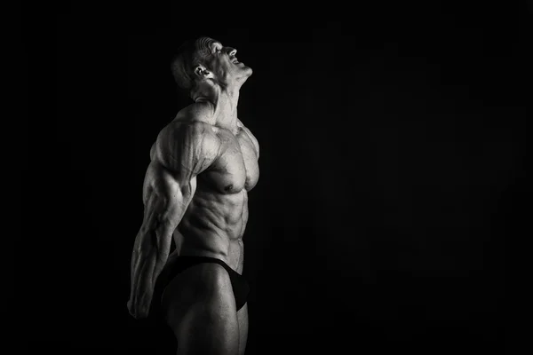 Muscular, fisiculturista alívio em um fundo preto — Fotografia de Stock