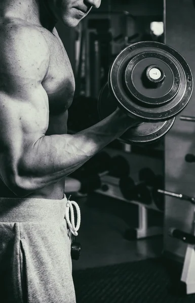 Ocupación con pesas en el gimnasio. Hombre fuerte con mancuernas — Foto de Stock