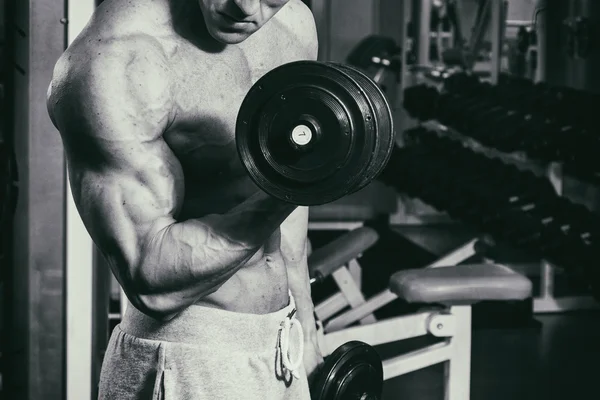 Occupazione con manubri in palestra. Uomo forte con i manubri — Foto Stock