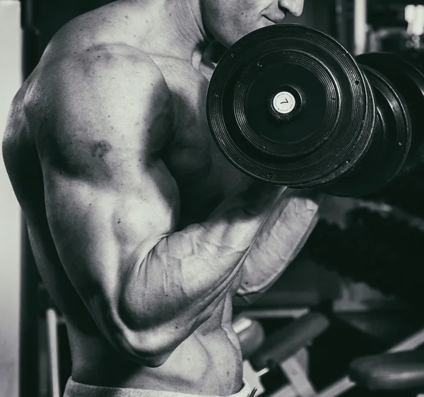 Ocupación con pesas en el gimnasio. Hombre fuerte con mancuernas —  Fotos de Stock