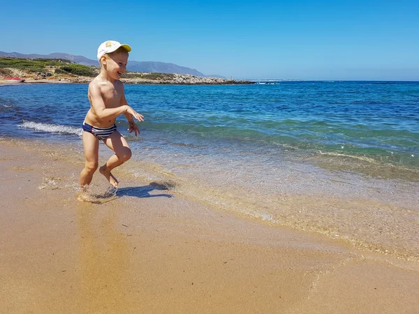 Ragazzo che riposa e corre lungo la spiaggia. Vacanze estive per bambini — Foto Stock