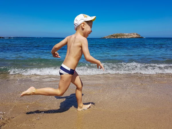 Ragazzo che riposa e corre lungo la spiaggia. Vacanze estive per bambini — Foto Stock