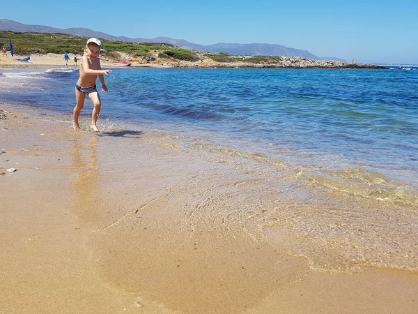 Junge rastet aus und läuft am Strand entlang. Sommerferienprogramm für Kinder — Stockfoto