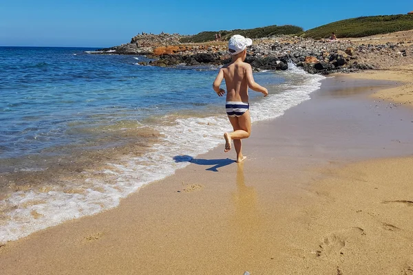 Junge rastet aus und läuft am Strand entlang. Sommerferienprogramm für Kinder — Stockfoto