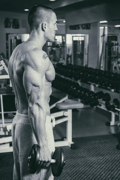 El hombre en el gimnasio bombeando músculos abdominales en un simulador especial . —  Fotos de Stock