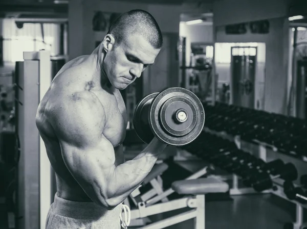 Mannen i gymmet pumpa buken muskler i en speciell simulator. — Stockfoto