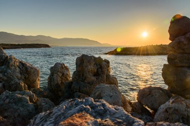 Akşam denizde güzel gün batımı kayalar ön planda