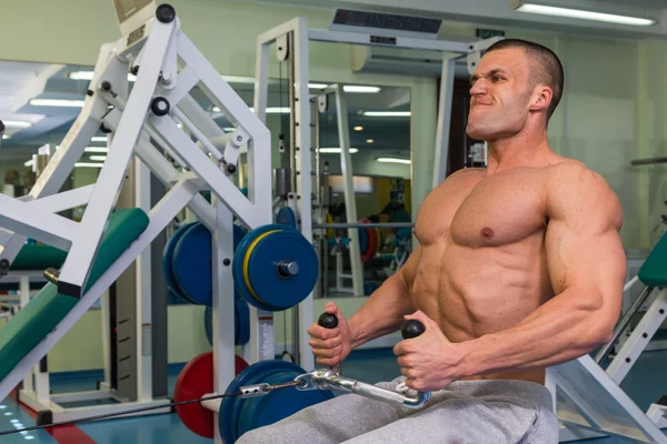 Silný muž pracuje na simulátoru v tělocvičně — Stock fotografie