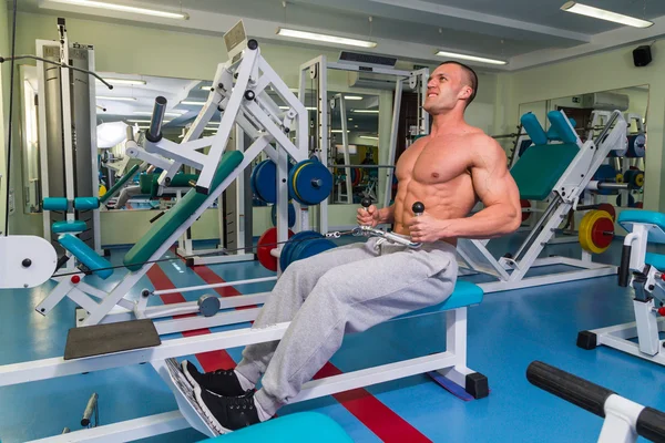 Silny człowiek jest zaangażowany na symulatorze w siłowni — Zdjęcie stockowe