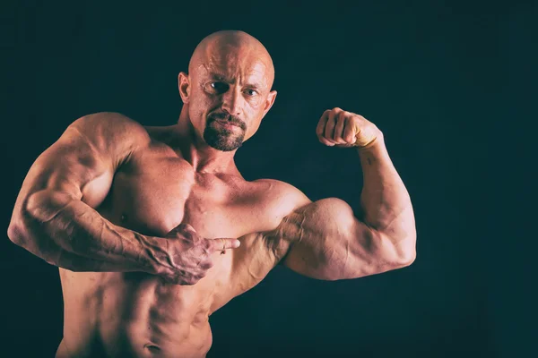 Muscular, relief body bodybuilder on a black background. Black a — Stock Photo, Image