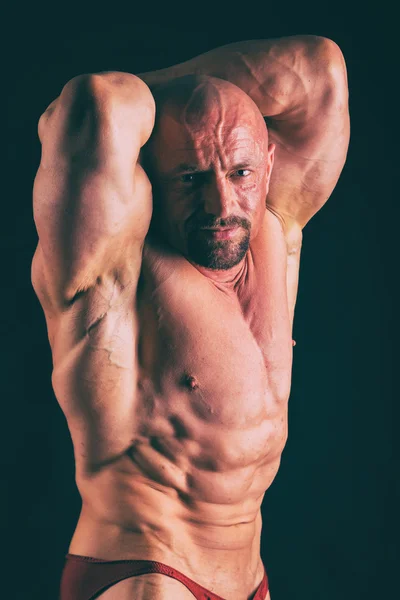 Musclé, bodybuilder de soulagement sur un fond noir. Noir a — Photo