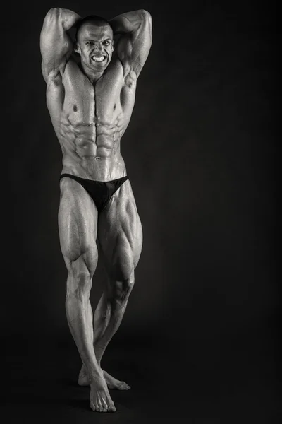 Очень мускулистый красивый спортивный мужчина на черном фоне — стоковое фото