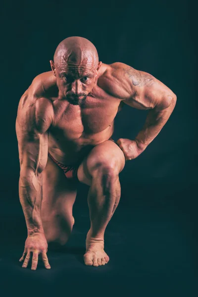 Muscular, relief body bodybuilder on a black background. Black a — Stock Photo, Image