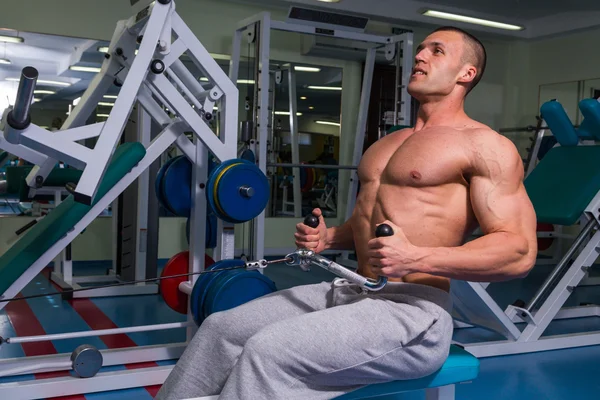 En stark man är engagerad på en simulator i gymmet — Stockfoto