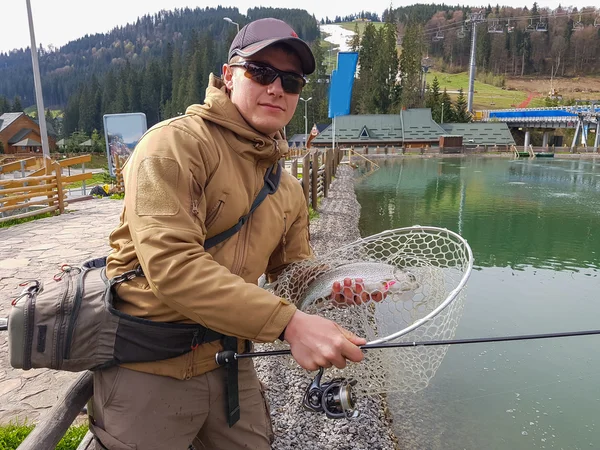 Forellenangeln auf dem See. Fischer fängt eine Forelle auf dem See — Stockfoto