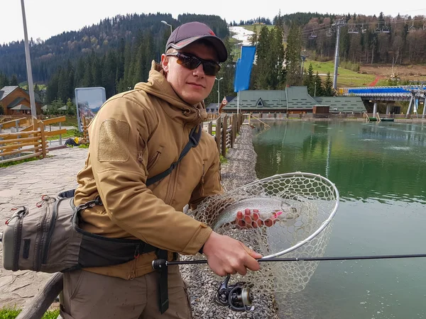 Pesca alla trota sul lago. Pescatore cattura una trota sul lago — Foto Stock